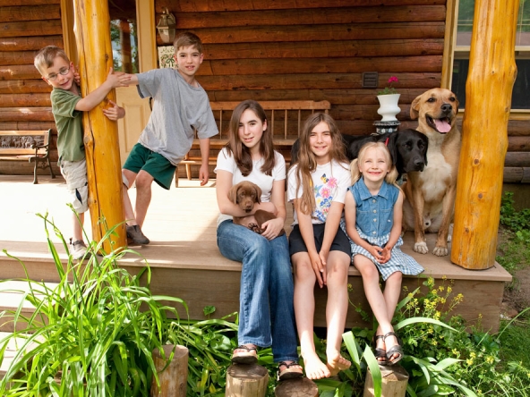 A group of smiling kids, accompanied by their three pets, enjoy their time in their dream home.