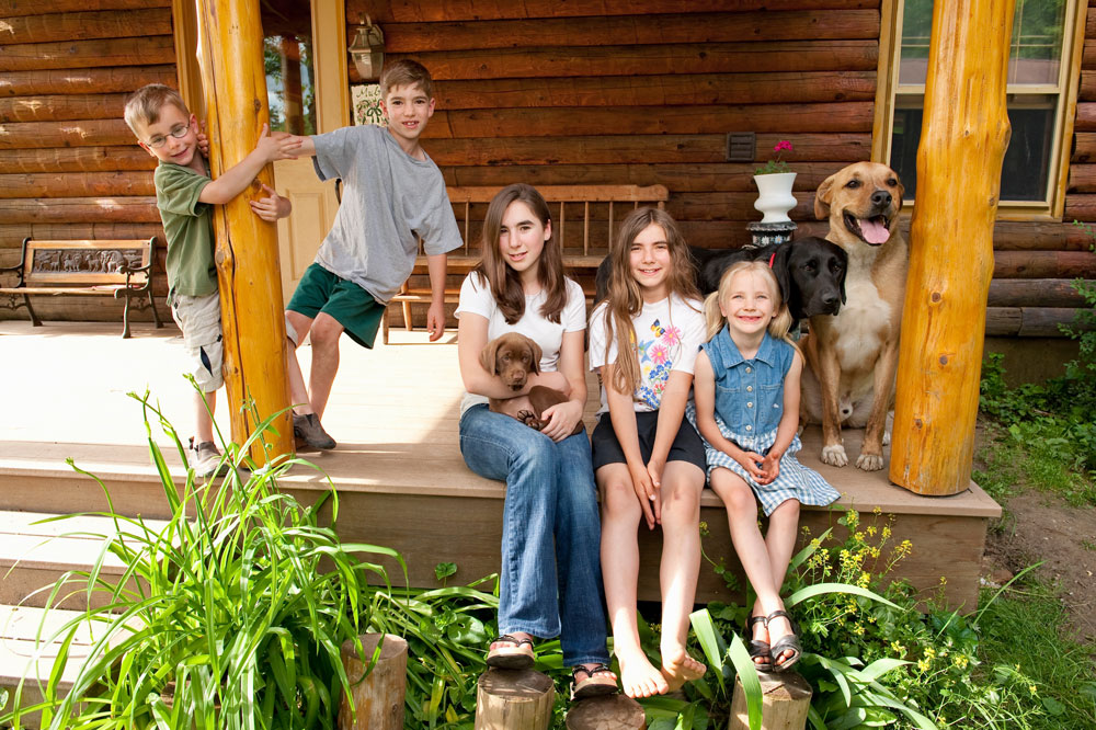 A group of smiling kids, accompanied by their three pets, enjoy their time in their dream home.